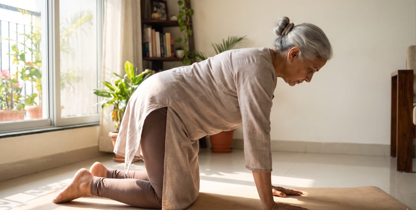 Woman doing a gentle stretching exercise on a mat at home to relieve lower back pain