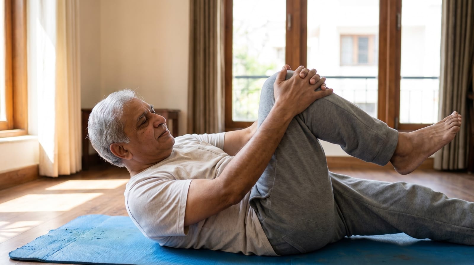 Person lying on a mat at home gently pulling one knee toward the chest, one of the exercises in the table below