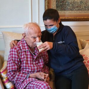 helping elderly in drinking milk
