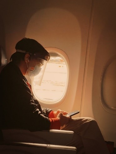 An elderly wearing a mask and face shield when traveling