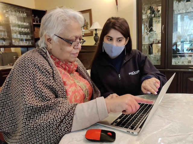 A senOcare professional offering tech assistance to an elderly lady 