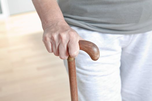 An elderly woman using a stick for walking support
