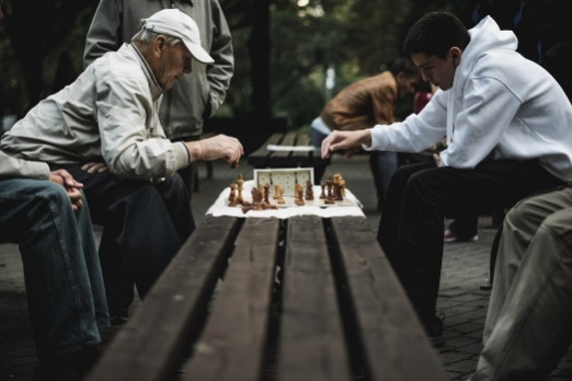 An elderly man engaged in a chess game with his son